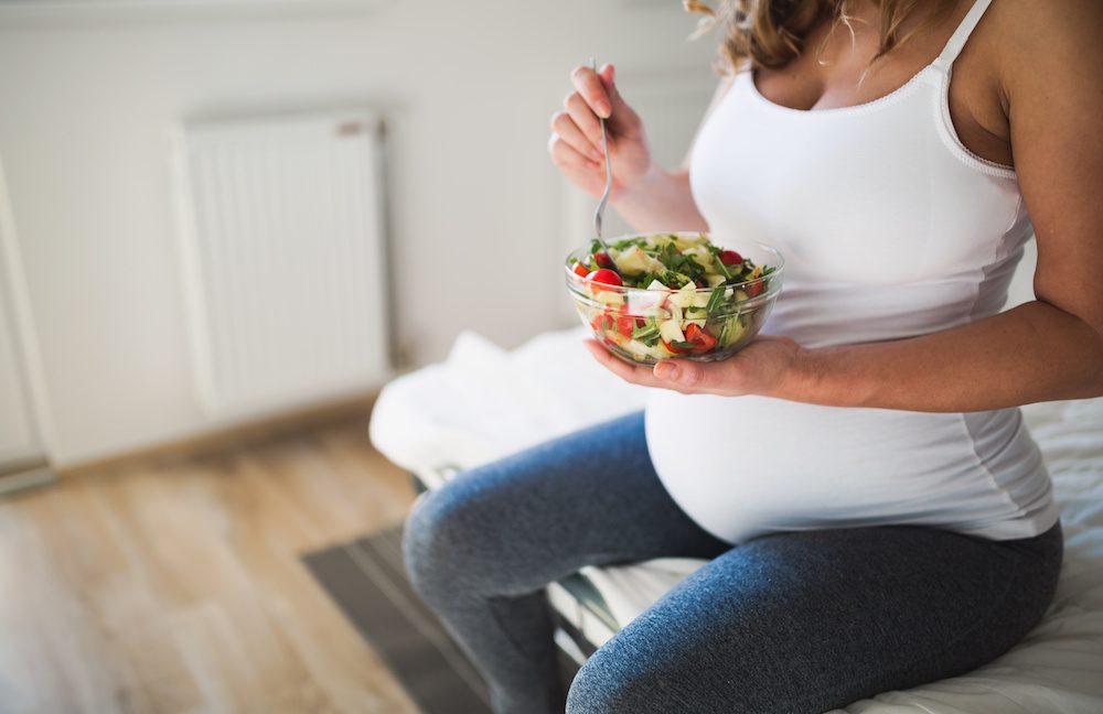 pregnant woman eating salad